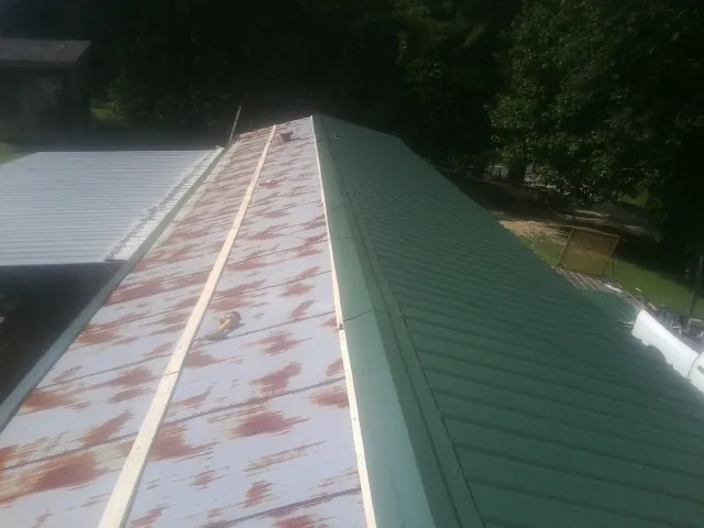 Old rusted panels beside newly installed green metal roofing — Wind Damage Roof Repair by Roofing Brothers in Toulon