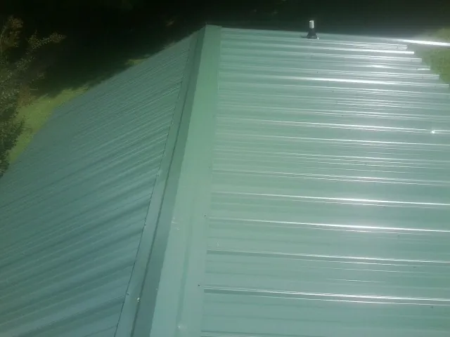 New green metal panels meeting at the ridge of a roof — Flat Roof Repair work by our crew in Toulon