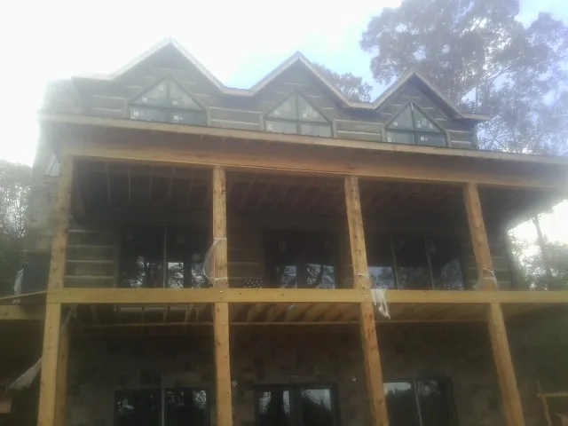 Dormers and porch framing on a large log home under construction — Roof Coating work by our crew in Toulon
