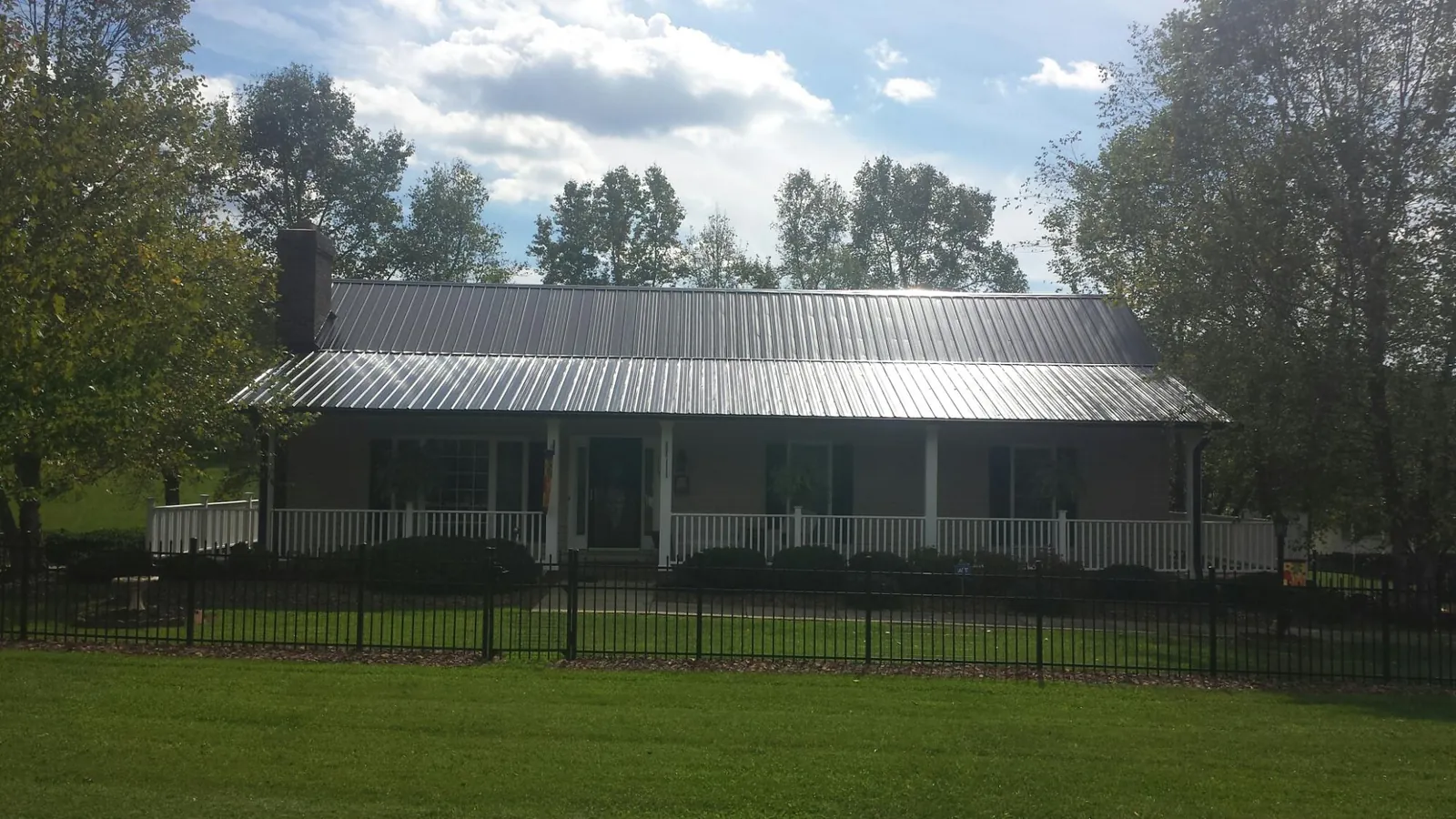 Gray metal roof on a brick ranch with a full width front porch — Gutter Guard Installation work by our crew in Toulon