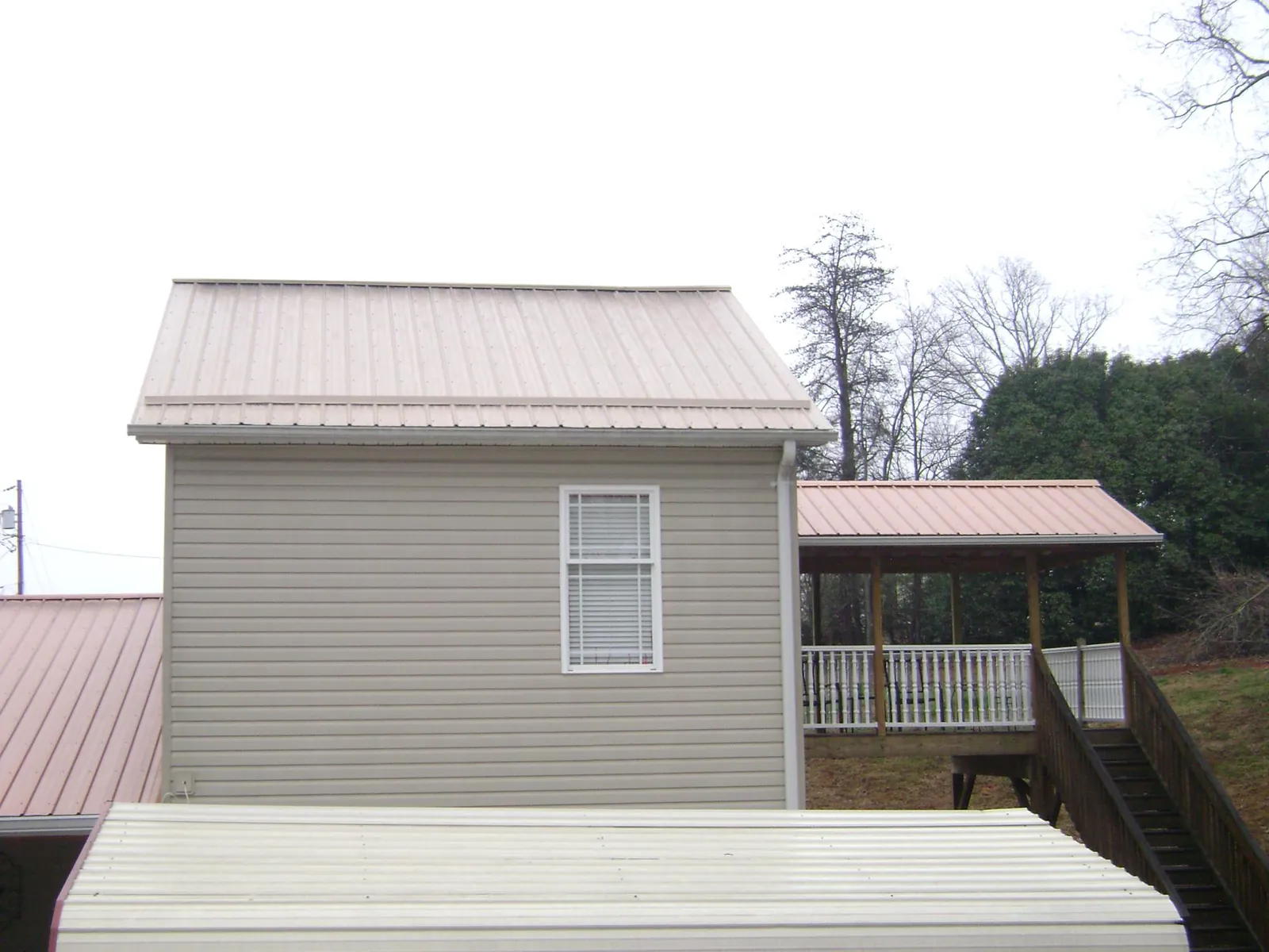 Tan metal roofs on a two story addition and attached porch, from a Roof Replacement job in Toulon