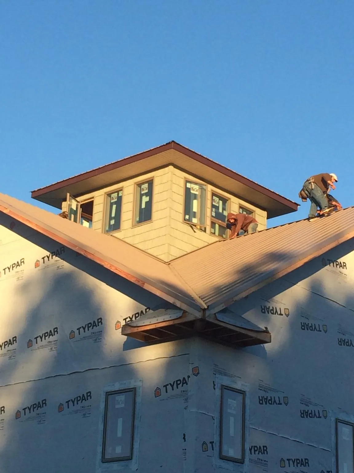 Roofers working around a rooftop cupola on a new metal roof at sunset — Roof Waterproofing in Toulon by Roofing Brothers